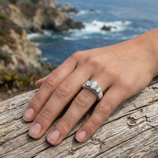 Hand wearing a diamond ring with a scenic ocean background