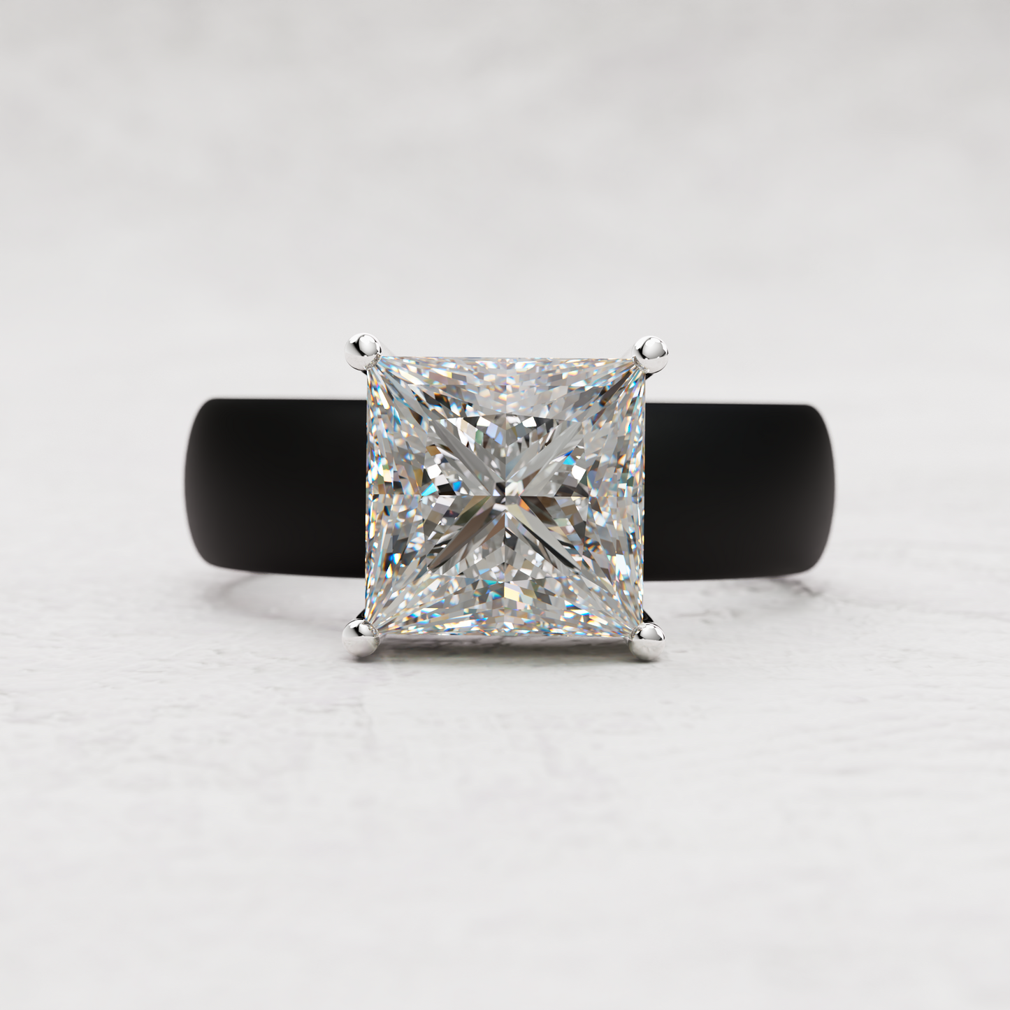 A princess-cut diamond ring with a silver-toned four-prong setting and a matte black band, centered on a light gray textured background.